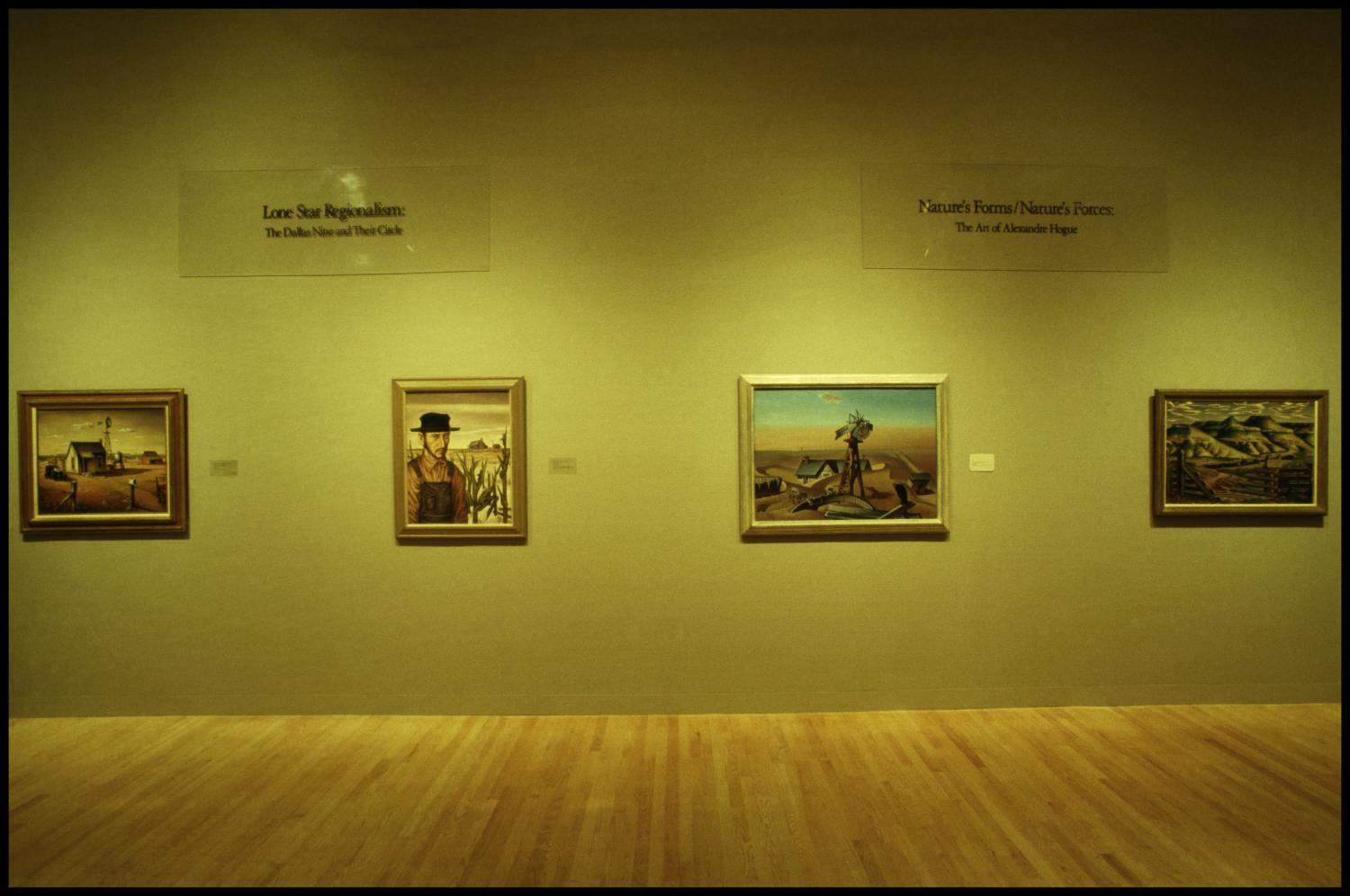 Gallery view of the Dallas Museum of Art's 1985 exhibition Lone Star Regionalism: The Dallas Nine and Their Circle, with framed paintings by the group on display.